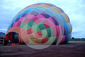 Process of inflation and preparation of hot air balloon at sunrise for flight in cloudy sky