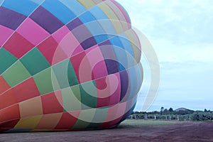 Process of inflation and preparation of hot air balloon at sunrise for flight in cloudy sky