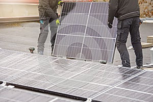 The process of installing solar panels. Solar panel installers work on the roof. Installers carry solar panel module to