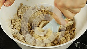 Process of kneading raw dough for gingerbread cookies, close up. Female hand kneads dough in bowl using cooking vane. Making cooki