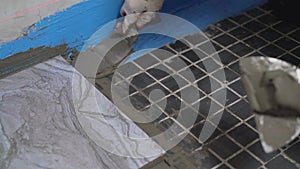 The process of laying ceramic floor tiles. Spreading wet mortar before applying tiles. Applying tile adhesive to the