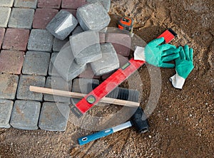 Process of laying paving stones in layers. Brick pathway paving equipment top view: hammer, level, bricks, gloves, bucket with