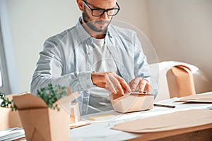 Process of making beautiful little wooden box. Print house worker in white clothes is indoors