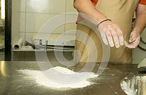 The process of making bread. The chef kneads the dough by hand. The chef`s hands are adding flour