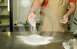 The process of making bread. The chef kneads the dough by hand. The chef`s hands are adding flour