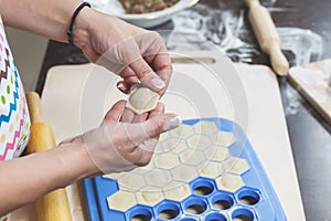 The process of making delicious homemade dumplings. Female hands hold freshly dumplings on the background of kitchen workspace