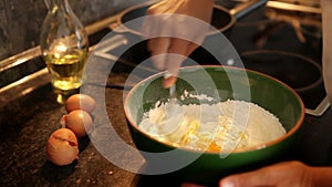 A process of making dough for pancakes: flour being mixed with eggs