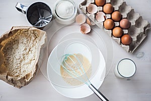 Process of making the dough, woman`s hand whips eggs and flour in bowl Flat lay composition of ingredients and batter.selective