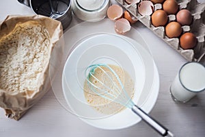 Process of making the dough, woman`s hand whips eggs and flour in bowl Flat lay composition of ingredients and batter.selective