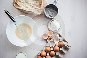 Process of making the dough, woman`s hand whips eggs and flour in bowl Flat lay composition of ingredients and batter.selective