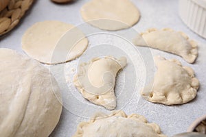 Process of making dumplings (varenyky) with mushrooms. Raw dough with filling on white table, closeup