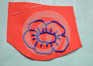 Process of making a flower beaded brooch - contour on felt embroided with blue beads - master class