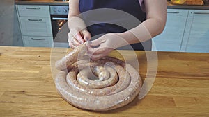 the process of making homemade grilled sausage from minced meat. the cook fills the intestines with minced meat.