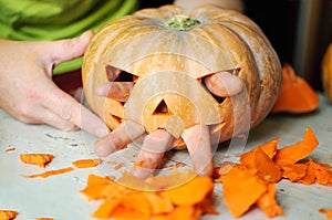 Process of making Jack-o-lantern. Funny picture of Halloween pumpkin monster face with male fingers.