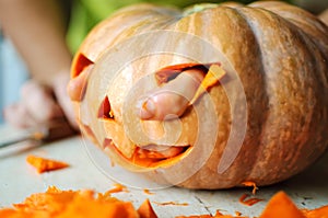 Process of making Jack-o-lantern. Funny picture of Halloween pumpkin monster face with male fingers.