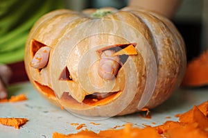 Process of making Jack-o-lantern. Funny picture of Halloween pumpkin monster face with male fingers.