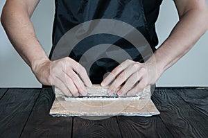 Process of making maki sushi. Cook chef hands preparing rolls with cheese, avocado and sesame seeds on wooden board