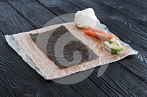 Process of making maki sushi. Cook chef hands preparing rolls with cheese, avocado and sesame seeds on wooden board