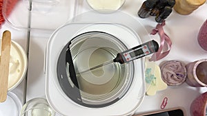 The process of making a massage candle using ingredients oils and wax measure weigh stir add close-up of women's