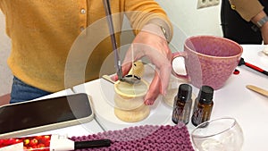 The process of making a massage candle using ingredients oils and wax measure weigh stir add close-up of women's