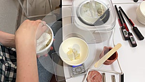 The process of making a massage candle using ingredients oils and wax measure weigh stir add close-up of women's