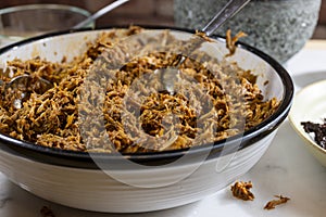 Process of making pulled pork with red ancho chili paste on a marble top kitchen counter photo