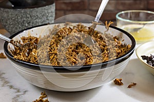 Process of making pulled pork with red ancho chili paste on a marble top kitchen counter photo