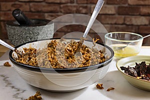 Process of making pulled pork with red ancho chili paste on a marble top kitchen counter photo