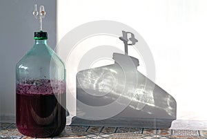 The process of making red homemade wine. A 20 liter glass bottle with a must