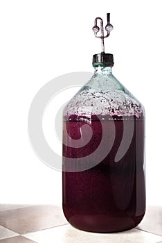 The process of making red homemade wine. A 20 liter glass bottle with a must with an airlock in a cork.