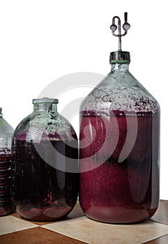 The process of making red homemade wine. Bottles with a must with an airlock in a cork.