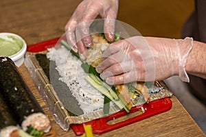 Process of making sushi and rolls. Close-up of man chef hands preparing traditional Japanese food at home or in restaurant on