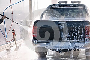 Process of man washing his car in a self-service car wash station. Back view