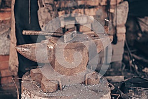 Process metal with hammer on anvil in forge. Strike iron outdoors in workshop with fire. Metalworking, blacksmithing.