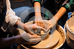 The process of modeling clay dishes on a potter`s wheel, the hands of a young girl and a child.