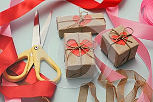Process of packaging gift boxes. Thanks gifts. Wedding presents. Pink ribbon and yellow scissors. Red carton hearts.