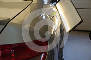Process Of Paintless Dent Repair On Car Body. Big Dent On Rear Car Fender. PDR Removal Course Training. photo