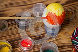 Process of paiting easter egg with orange brush, cans, wood