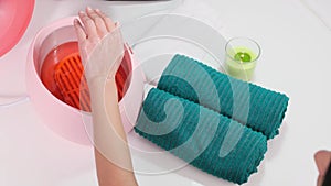 Process paraffin treatment of female hands in beauty salon, woman pulls her hand out of the parrafin bath.