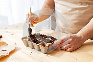 The process of planting seeds. A man pours earth with a small spatula into ecological peat moulds. Landscaping and