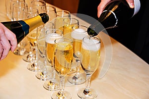 The process of pouring champagne into glasses. Bartenders prepare the table with alcoholic drinks. Close-up. Unrecognizable person