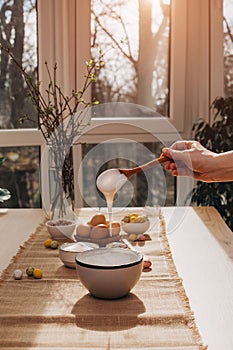 The process of preparing and decorating an Easter cupcake. Female hand putting white cream on round cupcake