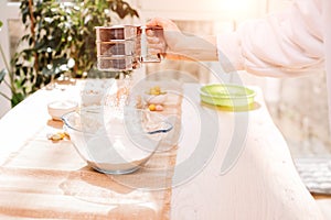 The process of preparing and decorating an Easter cupcake in the kitchen. Sifting flour with female hand