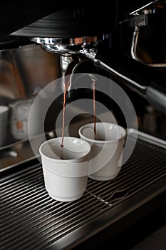 Process of preparing fresh fragnant espresso with rich taste on professional coffee machine in coffeeshop or cafe