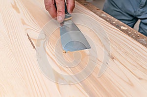 The process of puttying a wooden board. Spatula, putty, wooden board. Carpentry works