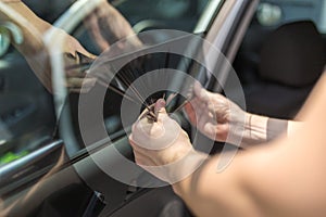 Close up of worker pulling off sun protection tinted foil from side car window photo