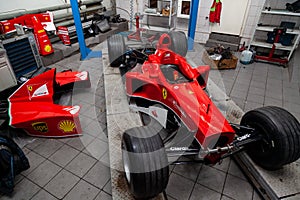 The process of repairing and restoring a red Ferrari Formula 1 car at a pitstop in the service station or a repair workshop on a