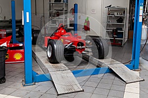 The process of repairing and restoring a red Ferrari Formula 1 car at a pitstop in the service station or a repair workshop on a