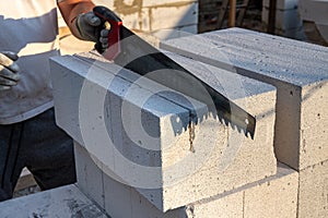 The process of sawing aerated concrete blocks with a hand saw. Construction of aerated concrete bricks, blocks.