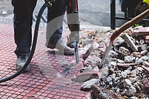 Process of sidewalk road repairing with jackhammer, builder worker with pneumatic hammer and drill equipment breaking asphalt